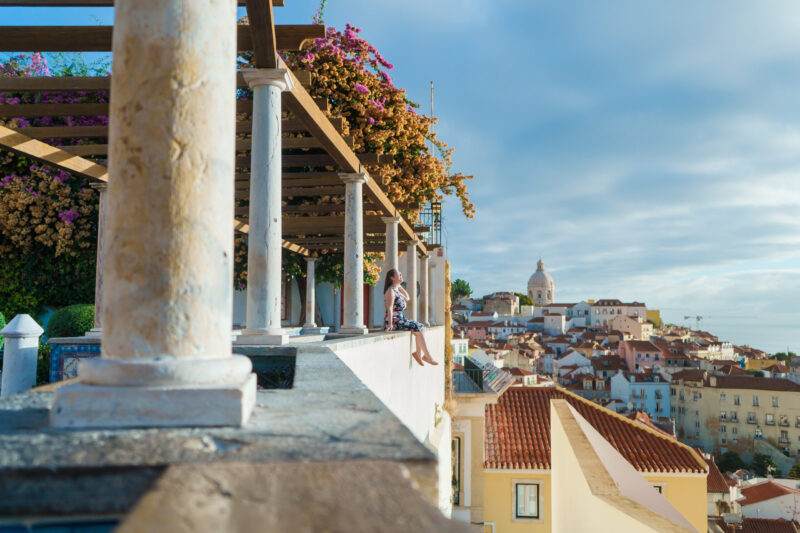 Pillars that line an overlook with the cityscape of Lisbon