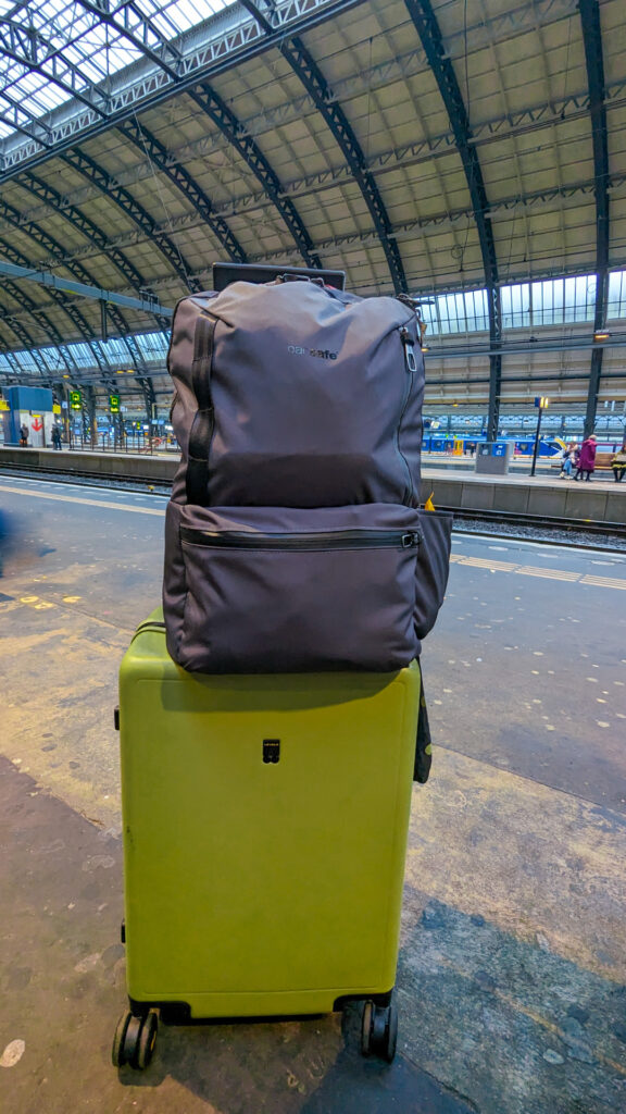 Lime green hardsided rolling suitcase with grey backpack on top.